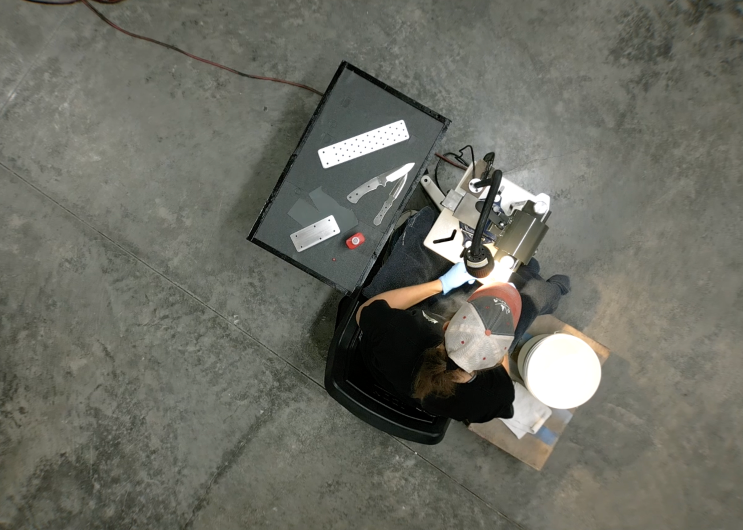 Person using a knife holder on a concrete floor with tools and equipment around
