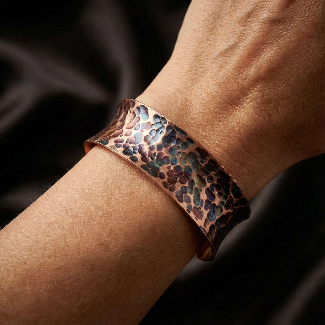 Copper bracelet with a textured pattern on a wrist against a dark background