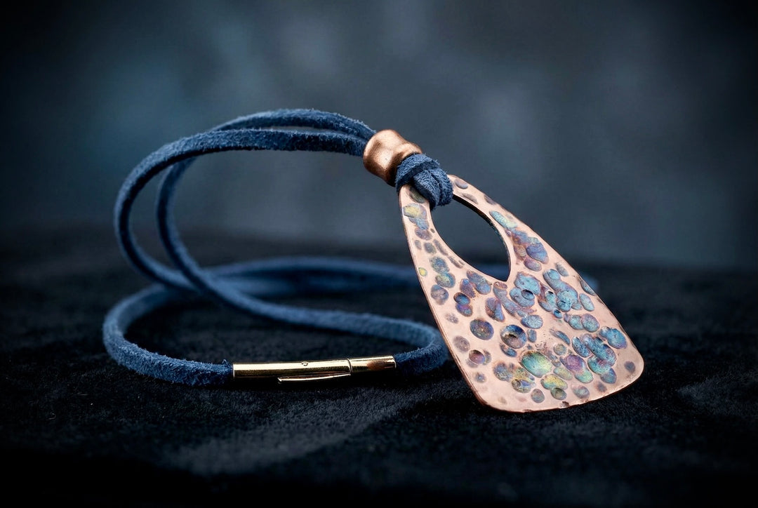 Navy blue leather cord necklace with a textured bronze pendant on a dark background