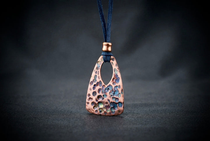 Copper pendant with a textured surface on a dark background