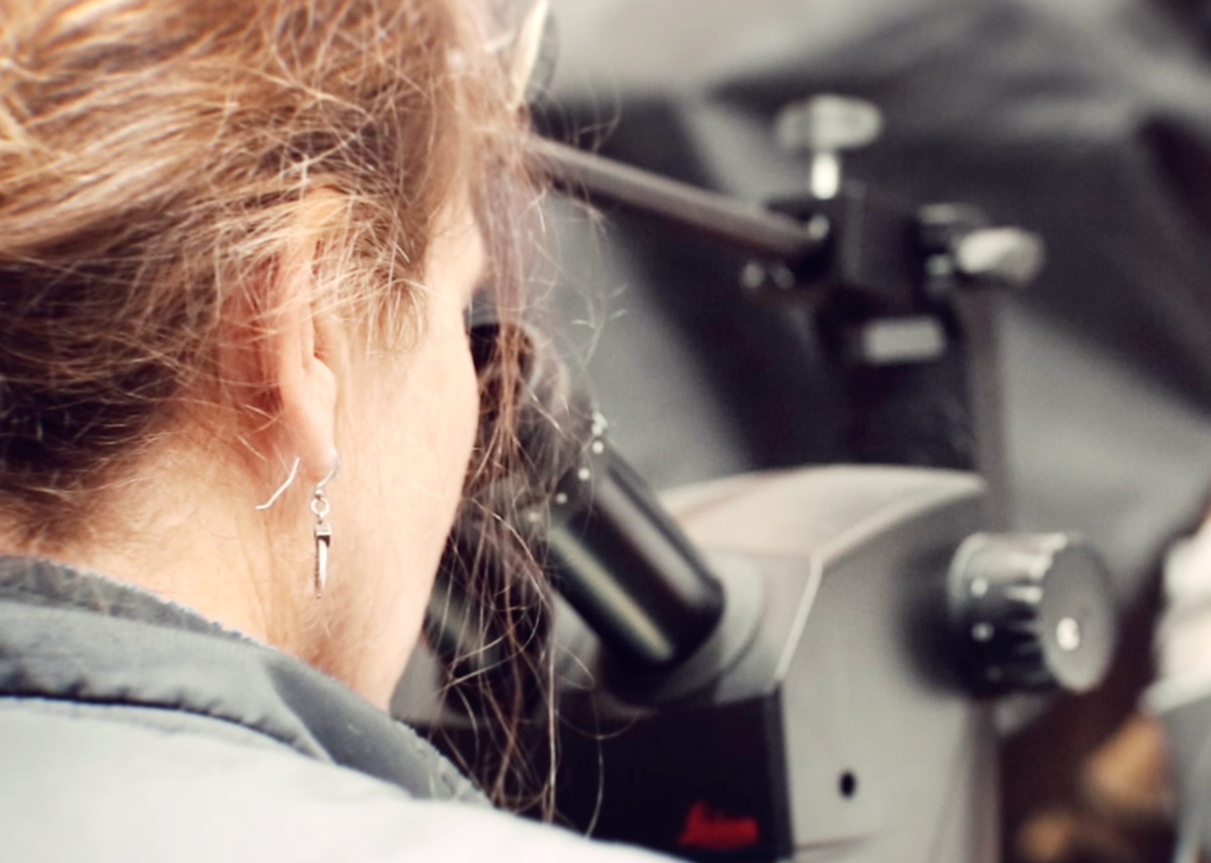 Person using a microscope with a blurred background