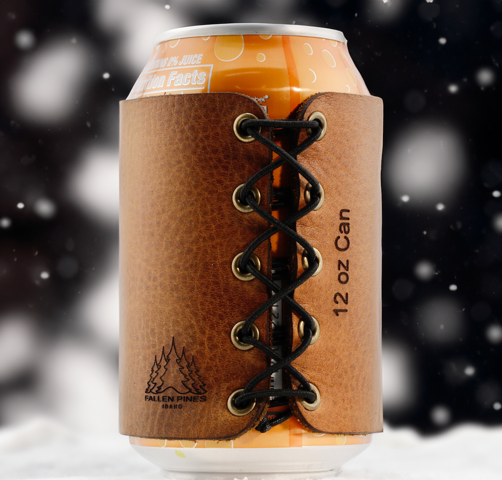 Brown leather can cooler with lace-up design holding a 12 oz can against a blurred snowy background