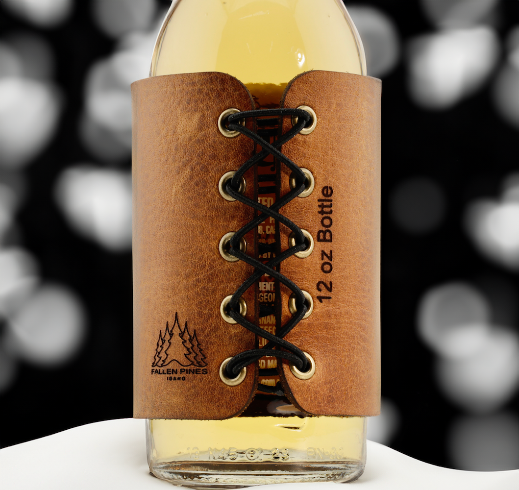 Wine bottle with a brown leather label featuring lace-up design and brand logo.