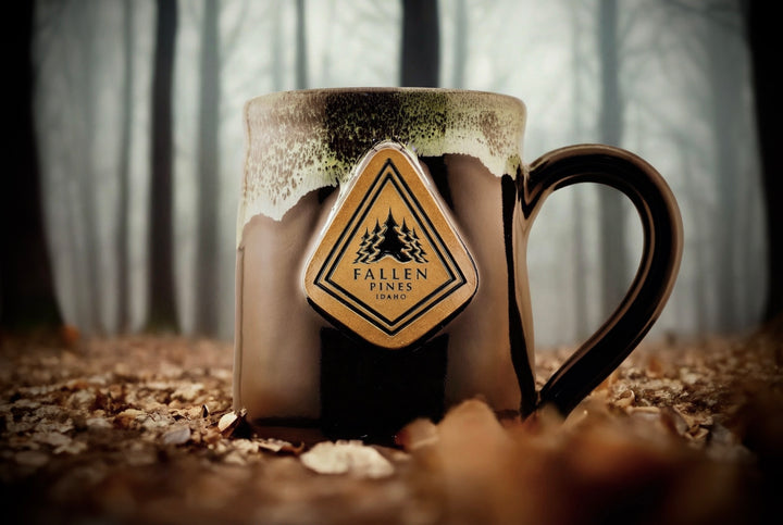 Mug with a 'Fallen' coffee dart label against a forest background