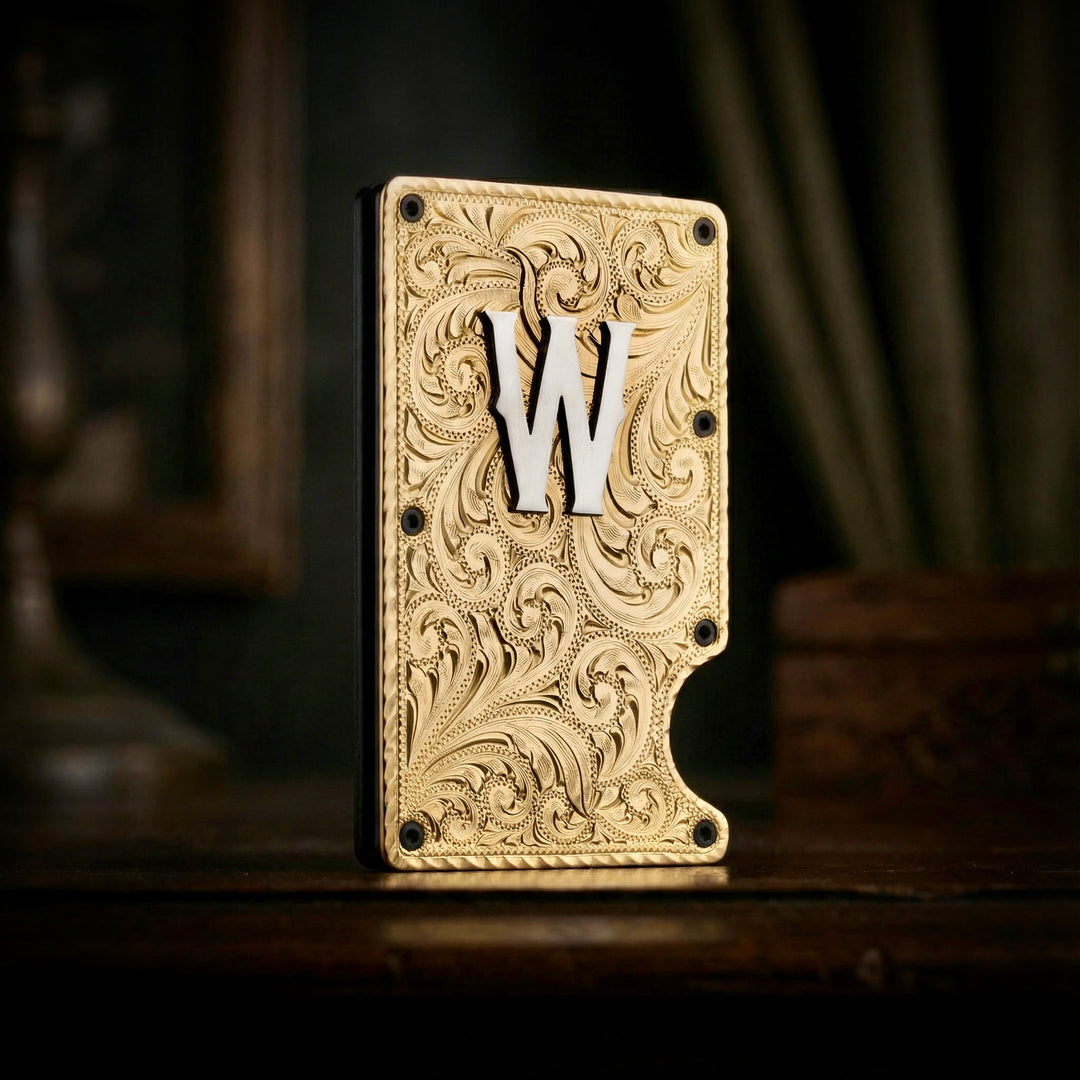 Decorative brass wallet with intricate patterns and a silver letter 'W' on a dark background