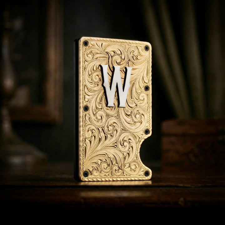 Decorative brass wallet with intricate patterns and a silver letter 'W' on a dark background