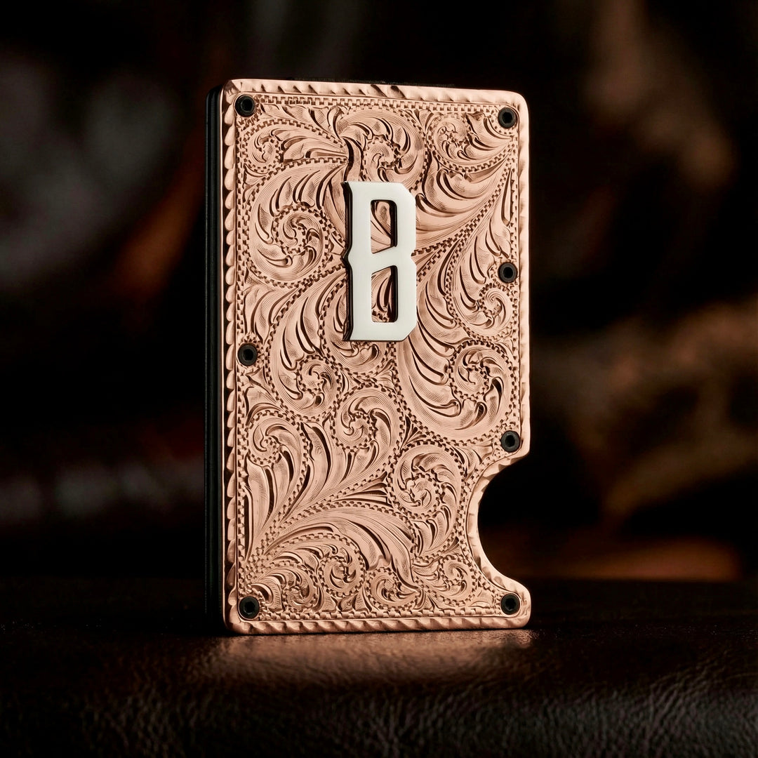 Decorative metal wallet with intricate patterns and a letter 'B' on a dark background