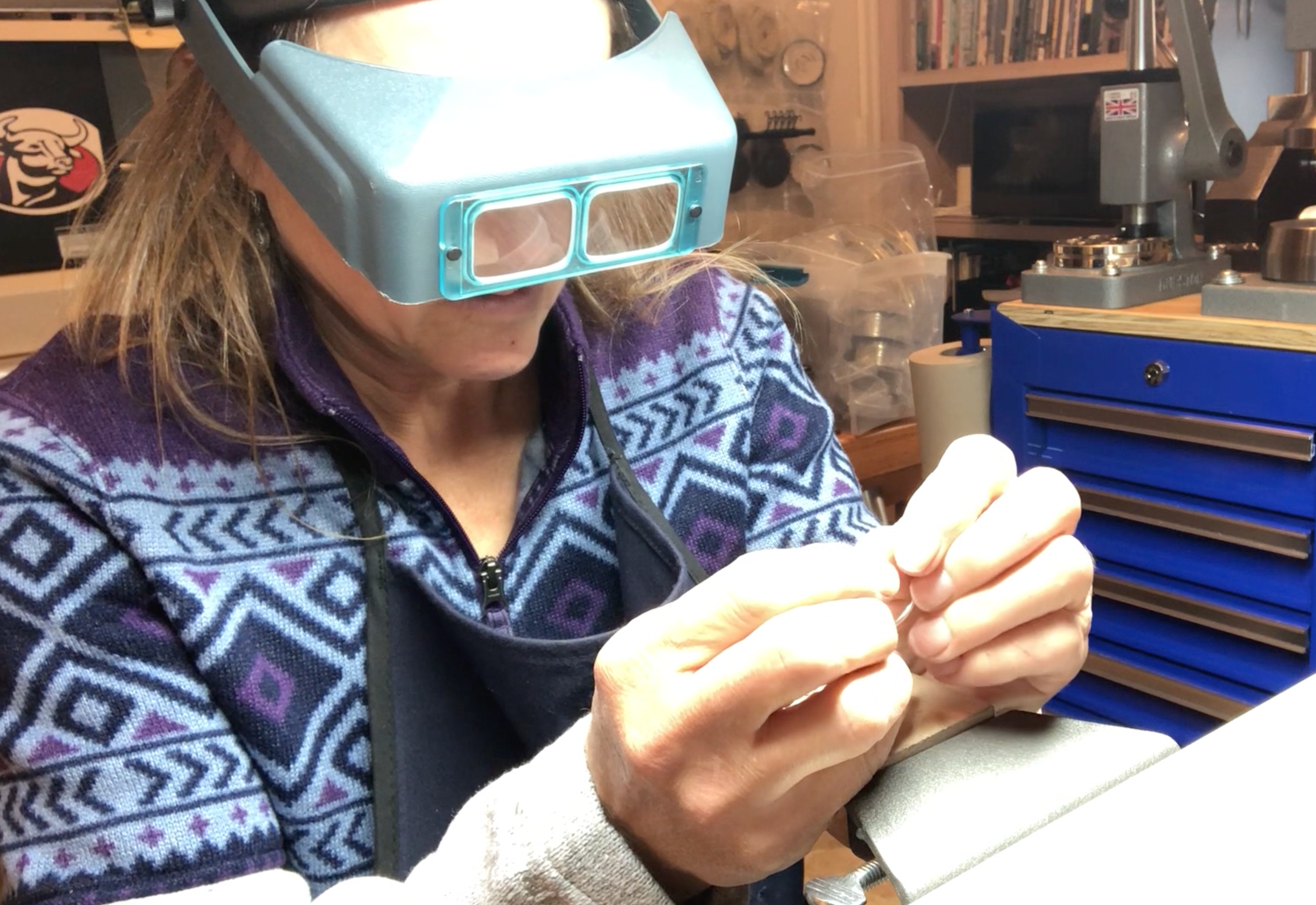 Person wearing magnifying glasses in a workshop setting
