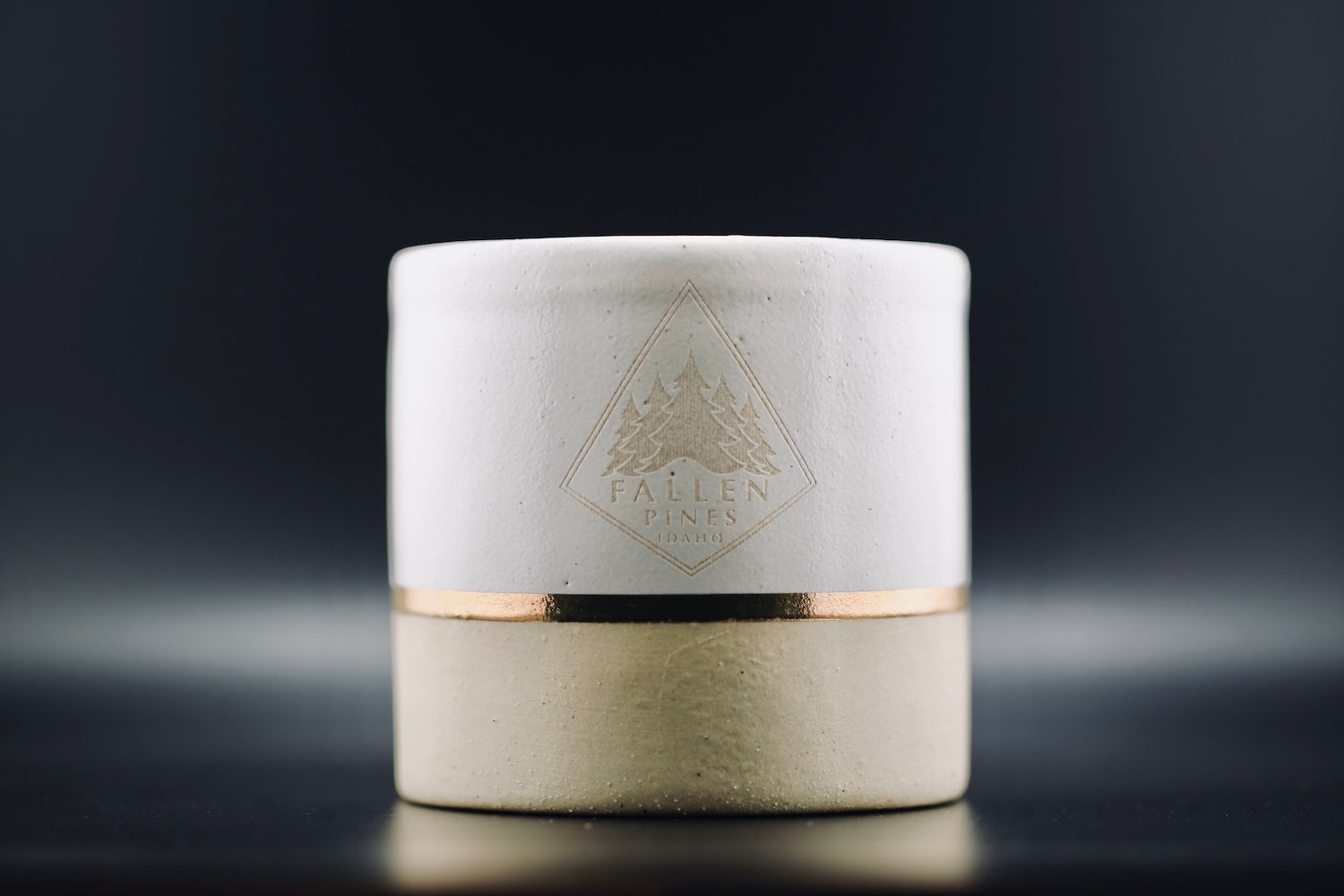 White ceramic container with gold accent and 'Fallen Pines' logo on a dark background