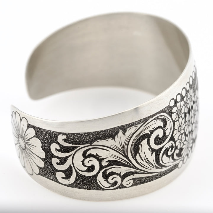 Silver cuff bracelet with black and white floral and leaf pattern on a white background