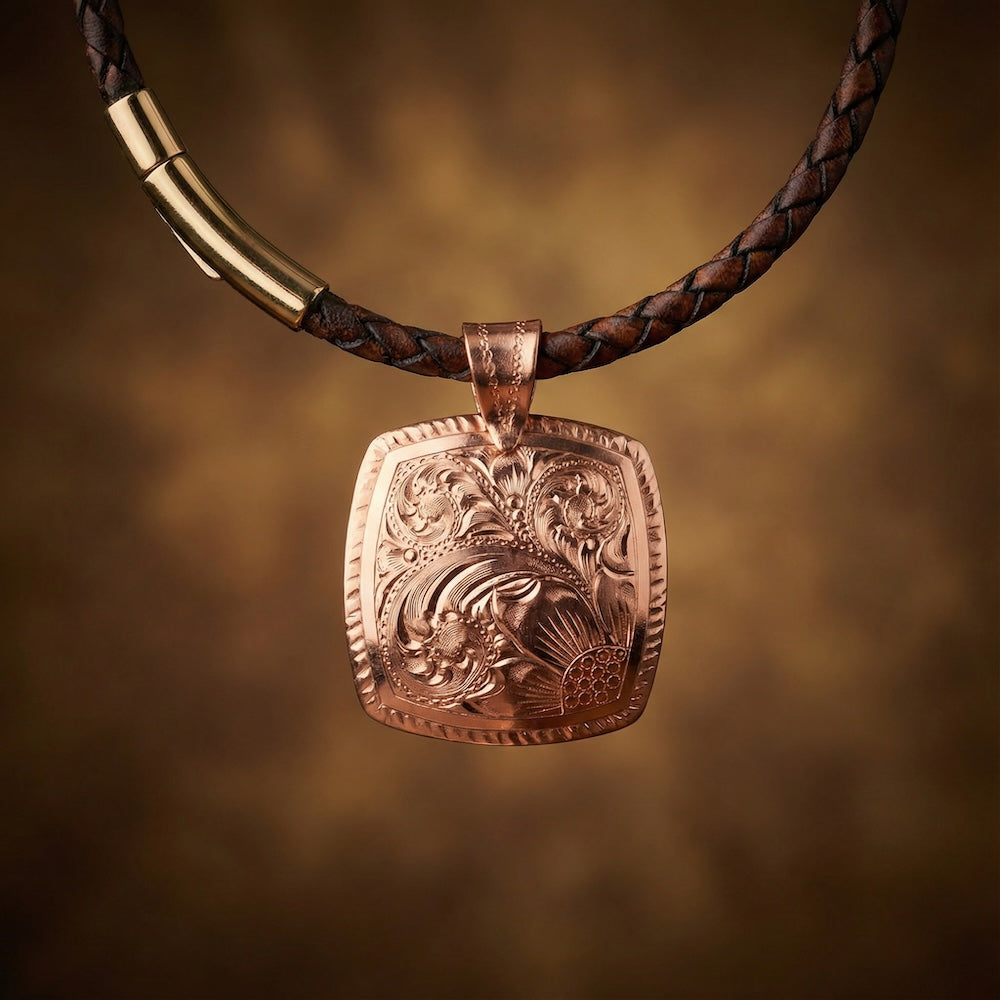 Bronze pendant on a braided leather strap against a warm brown background