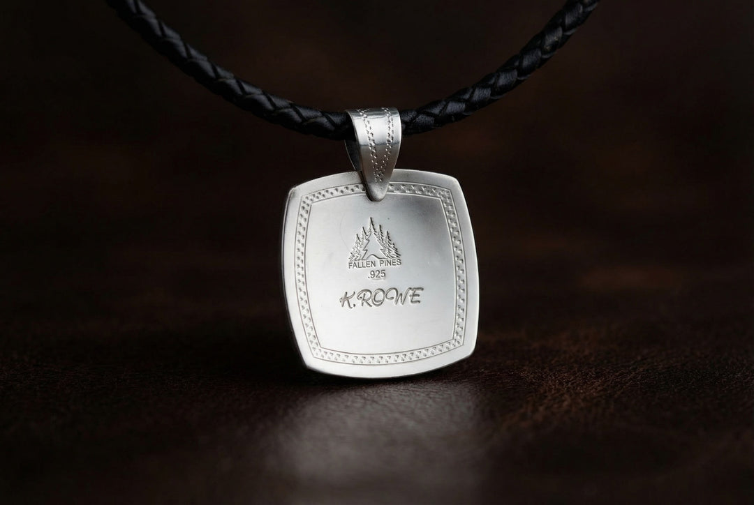 Silver pendant with engraved text on a dark background