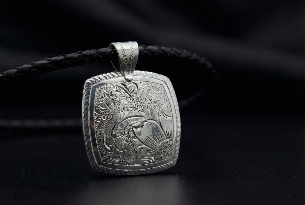 Silver pendant with intricate design on a black background