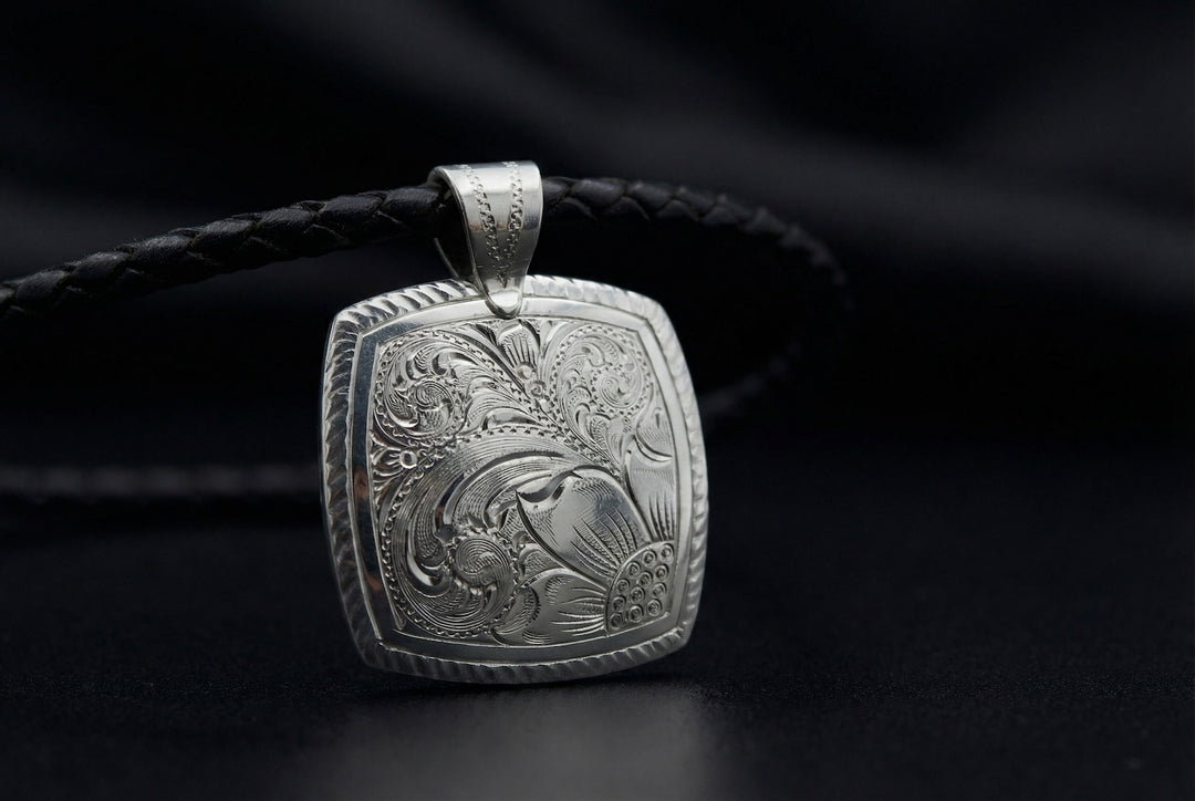 Silver pendant with intricate design on a black background