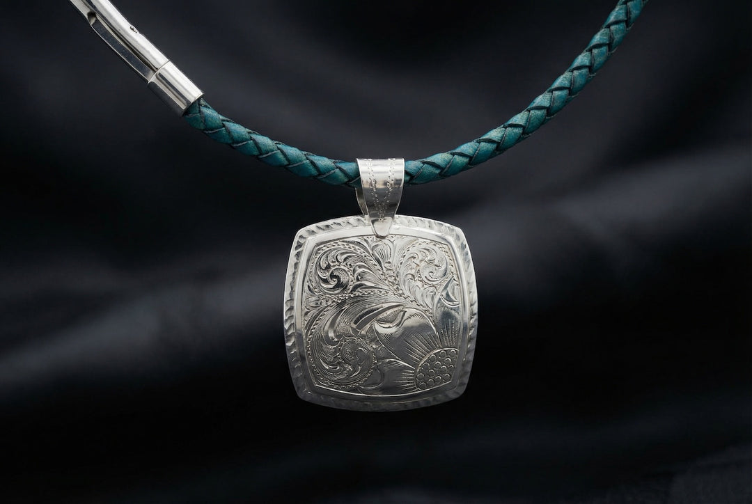 Silver pendant with intricate design on a green braided cord against a dark background