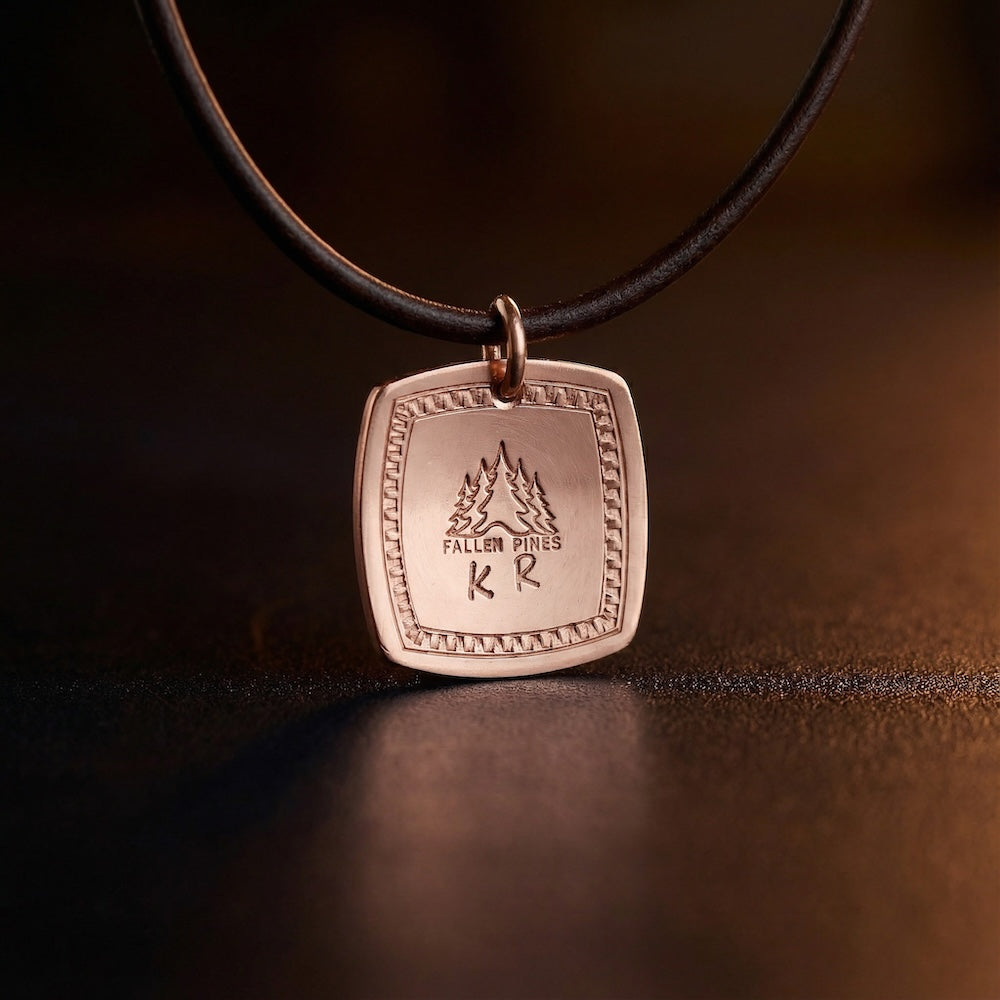 Bronze pendant with engraved text on a black cord against a dark background