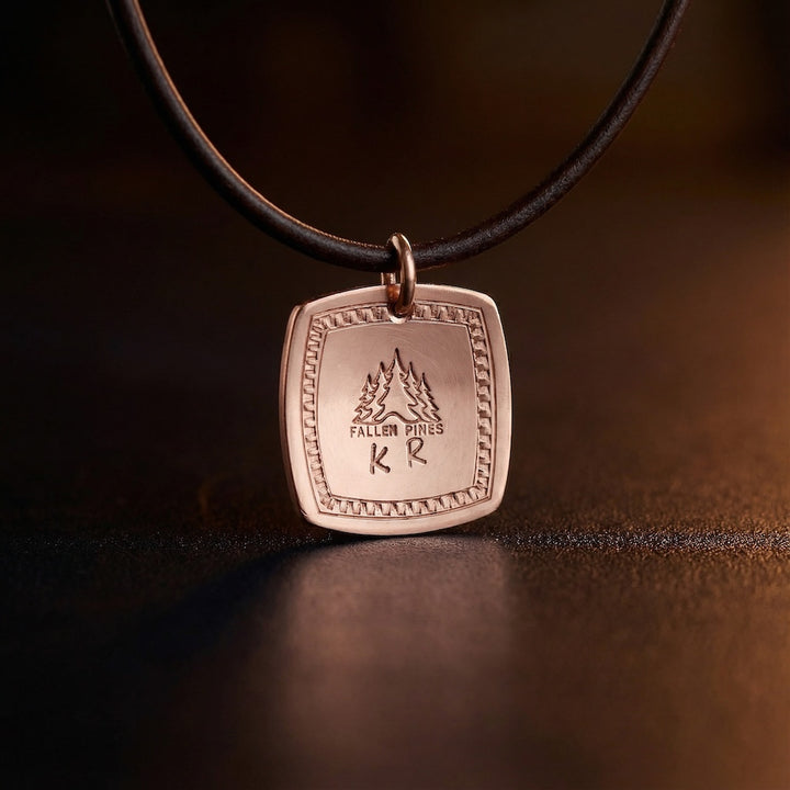 Bronze pendant with engraved text on a black cord against a dark background