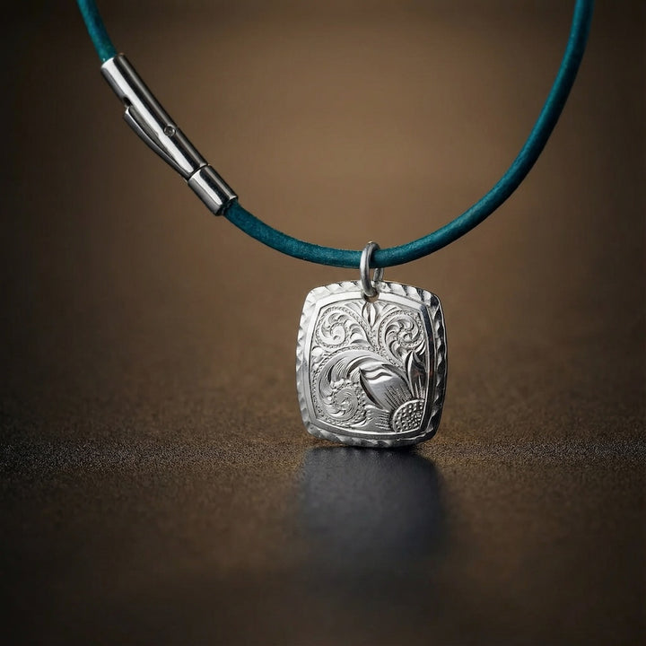 Silver pendant on a blue cord against a brown background