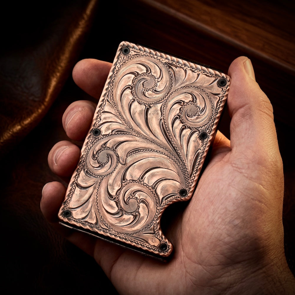 Hand holding a intricately designed metal object with swirling patterns.