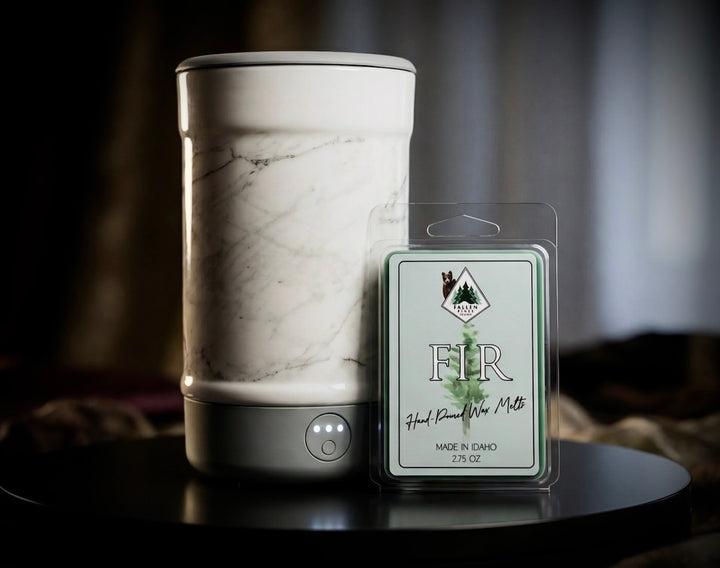 Marble-patterned wax warmer with a 'Fir' wax melt package on a dark surface.